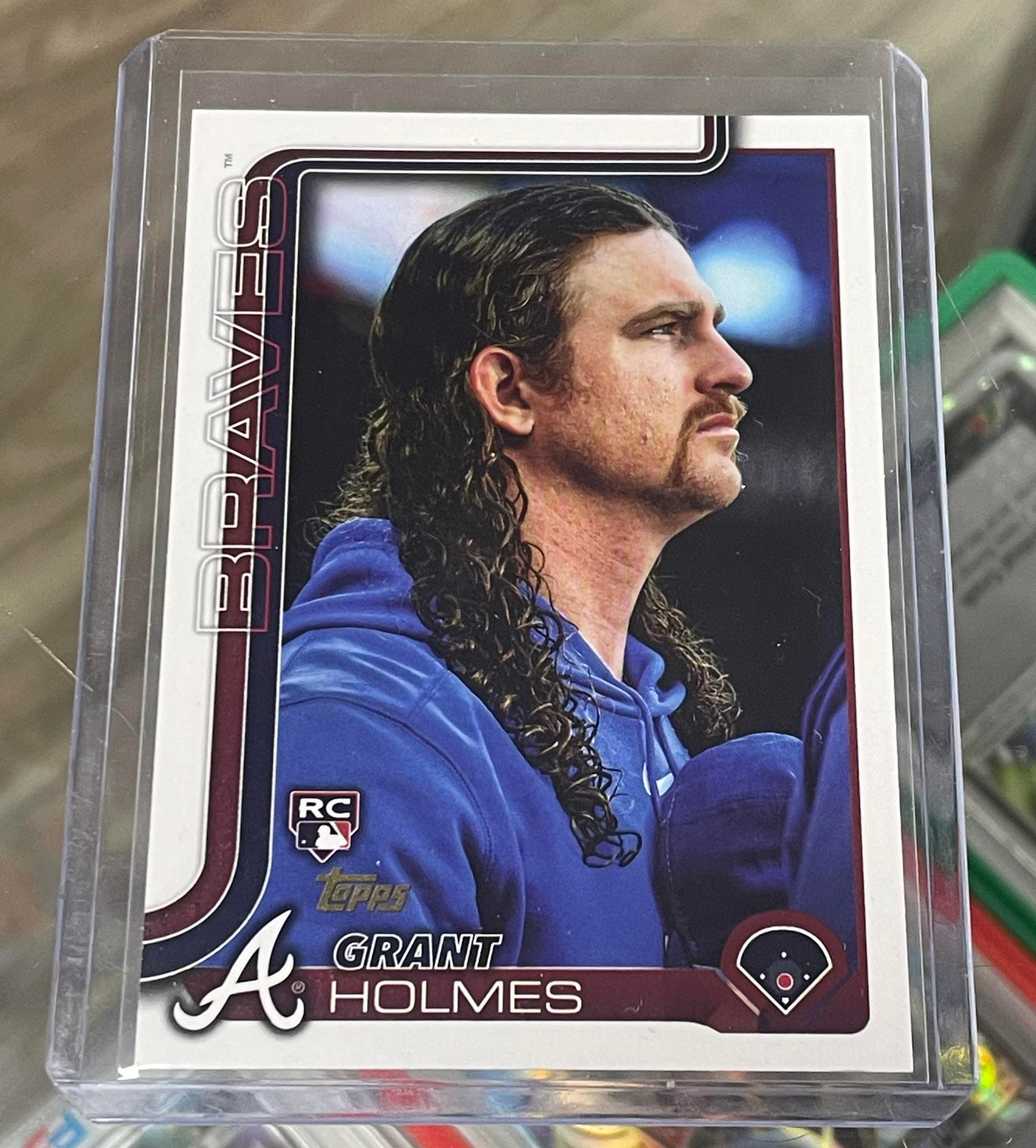 Grant Holmes Atlanta Braves rookie baseball card featuring his long curly hair and mustache.