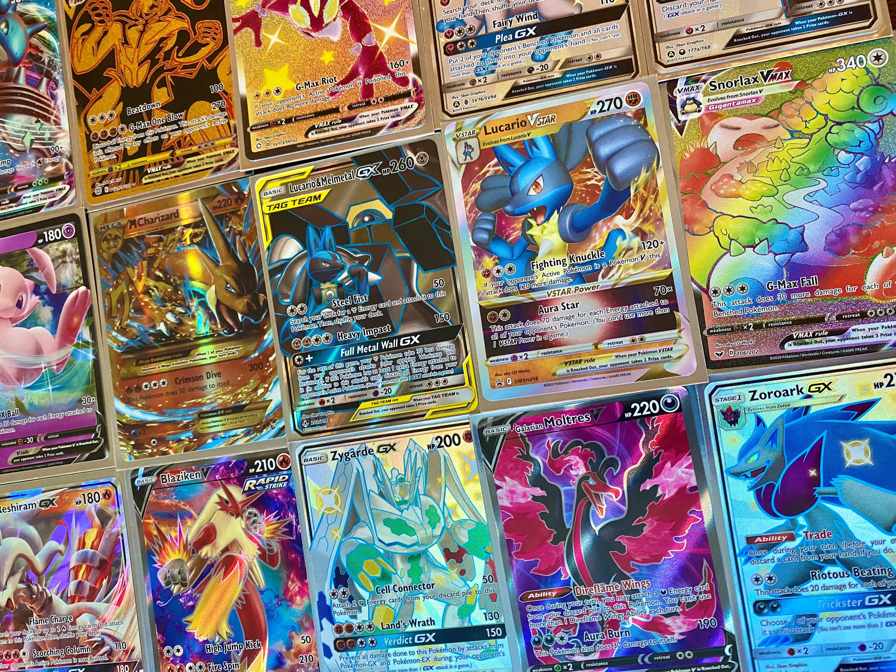 Various colorful and holographic Pokémon trading cards featuring characters like Lucario, Charizard, and Snorlax.