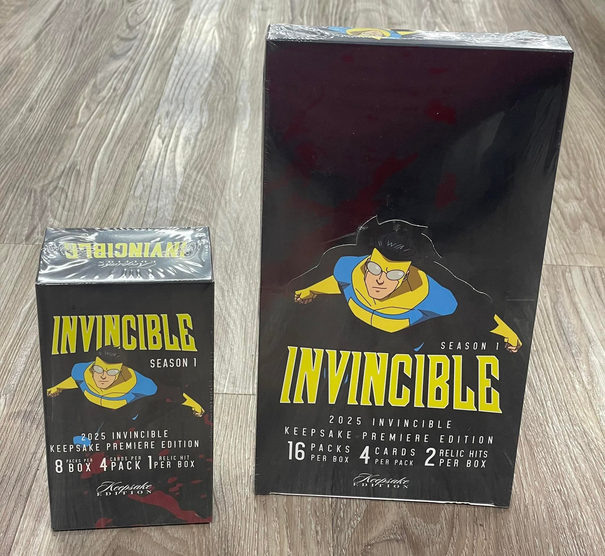 Two shrink-wrapped boxes of Invincible Season 1 Keepsake Premiere Edition trading cards on wood.
